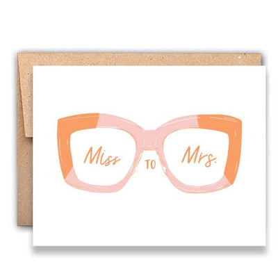 The Stack Paper Press Miss to Mrs. Letterpress Card features pink glasses with Miss and Mrs. on each lens, printed on luxurious cotton paper, and comes with a brown envelope.