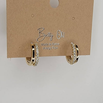 BETTYOH INC Huggie Hoops: gold plated earrings with a row of sparkling cubic zirconia, displayed on a brown card labeled Betty Oh! Made in Korea, Allergy Free.