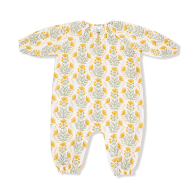 The Winter Dandelions Romper by Angel Dear is a long-sleeve baby romper made from organic cotton muslin, featuring yellow flowers and green leaves on white, with elastic cuffs and gentle cycle machine wash care.