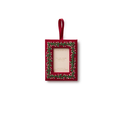 The Garland Embroidered Frame Ornament by Rifle Paper Co. is a small red rectangular bookcloth ornament with green and white embroidered foliage and a grosgrain ribbon loop for hanging, shown against a white background.