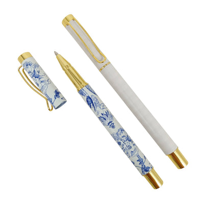 The Sweet Water Decors Blue Delft Metal Pen Set includes a fountain pen with a gold-accented, floral blue and white porcelain barrel reminiscent of blue delft. The removable cap has a matching floral design and gold clip, revealing the nib when placed aside.