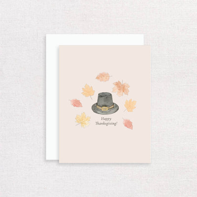 The Happy Thanksgiving Fall Greeting Card by Korynne and Company features a watercolor pilgrim hat with orange and yellow leaves, plus "Happy Thanksgiving!" on a light background.