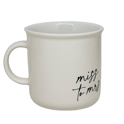 The Miss to Mrs. cream-colored 11oz campfire coffee mug by Sweet Water Decor features a handle and elegant black script, making it a perfect bridal shower gift for brides-to-be.