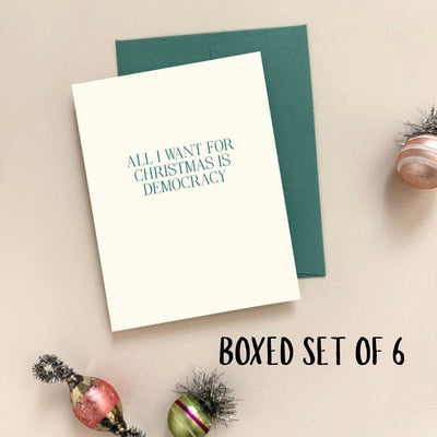 Missive's All I Want For Christmas Is Democracy Letterpress Cards, BOXED SET OF 6, feature cream cards with teal text and come with green envelopes—perfect for spreading festive cheer.