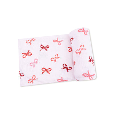 The Candy Cane Bows Ribbed Swaddle Blanket by Angel Dear showcases a soft, white ribbed fabric with an allover red and pink bows pattern, highlighted against a crisp white background.