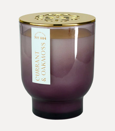 The Elum Currant & Oakmoss 21 oz Maeve Glass Candle features a purple jar with a decorative gold lid, offering a joyful ambiance with its soy wax fragrance.