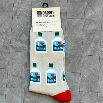 The I Love Ranch Socks from Barrel Down South feature a playful bottle design with vibrant red toes on a gray tiled backdrop. Theyre available in one size fits most, making them the perfect gift for ranch dressing enthusiasts.