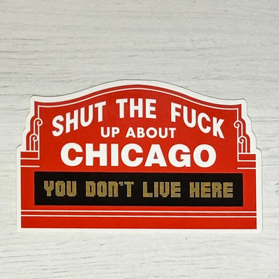 The Harebrained! STFU About Chicago Northside Sticker is a bold red and white 4-inch sticker with a marquee-style design that says: SHUT THE FUCK UP ABOUT CHICAGO. YOU DONT LIVE HERE, displayed on a light wood background.