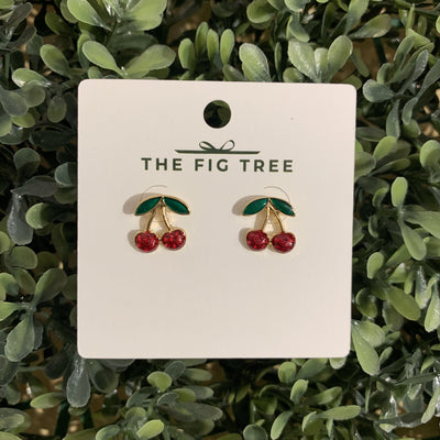 The Cherry Sweet Earrings by Girly, featuring charming cherry post earrings with red gems and green leaves (each about 1/2 long), are beautifully displayed on a leafy green card.