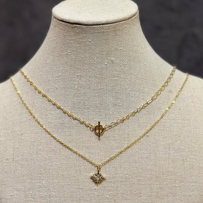 A display bust features two gold chain necklaces by Golden Stella: a shorter adjustable chain with a toggle clasp and the 17.5-inch Layla Necklace, which has a star-shaped pendant set with a clear gemstone.