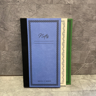Three Punch Studio Tiered Softcover Journals—a blue one with a fabric spine labeled Notes, a cream softcover, and a green—are stacked side by side against a gray textured background, each showing part of its cover.