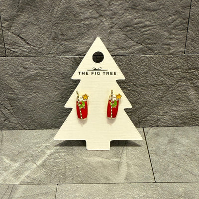 Christmas Cocktail Enamel Stud Earrings by Prep Obsessed Wholesale are shaped like red mugs with marshmallows and a gold star, displayed on a white, tree-shaped card labeled THE FIG TREE against a gray stone background.