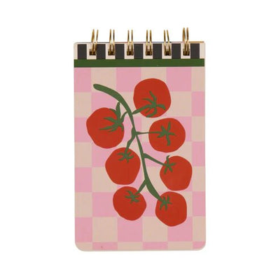 The A Dopo Tomato Twin Wire Notepad by Designworks Ink features hand-drawn tomato vines with seven red tomatoes on a pink and beige checkered backdrop. Its gold twin wire binding adds elegance, reminiscent of Mediterranean travels.