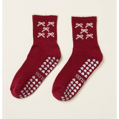Red socks with white bow patterns and heart designs on a beige background