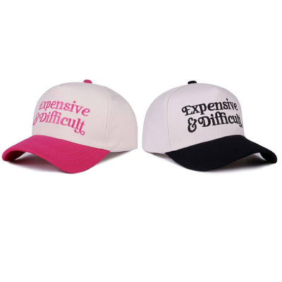 The 42POPS Expensive & Difficult Two Tone Baseball Caps include two light cotton, adjustable caps—one with a pink brim and text, the other black—both lightweight and breathable for comfortable all-day wear.