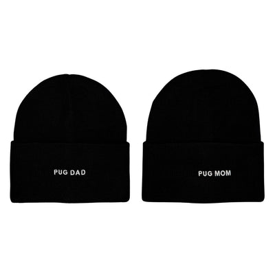 Two black HATPHILE beanies from the HatPhile Pug Mom & Pug Dad Embroidered Beanie set are shown side by side, one reading "PUG DAD" in white and the other "PUG MOM," both with white embroidery.