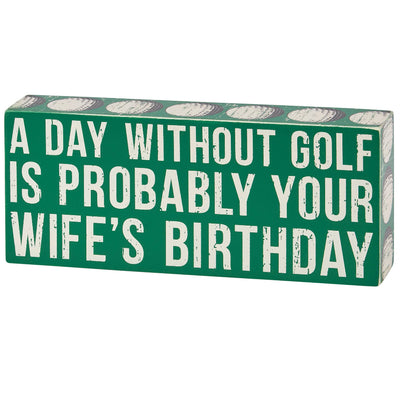 The Primitives by Kathy Your Wifes Birthday Box Sign is a green rectangular decor piece with bold, distressed white text: “A DAY WITHOUT GOLF IS PROBABLY YOUR WIFES BIRTHDAY.”.