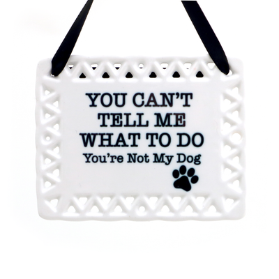 The Lenny Mud Youre Not My Dog Hanging Ceramic Tile is a white, rectangular plaque with a decorative border and black ribbon, featuring the words YOU CANT TELL ME WHAT TO DO Youre Not My Dog and a paw print—perfect for dog lovers.