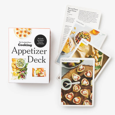 The New York Times Cooking Appetizer Deck by Penguin Random House LLC is pictured alongside vibrant recipe cards showcasing party appetizers like stuffed figs and cheese balls from NYT Cooking.