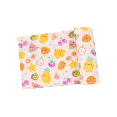 The Angel Dear Tropical Market Fruit Muslin Swaddle Blanket features cheerful cartoon fruits like pineapples, oranges, and strawberries, plus flowers on a white backdrop. Made from organic cotton muslin, this vibrant design is ideal for swaddles or a delightful baby gift.