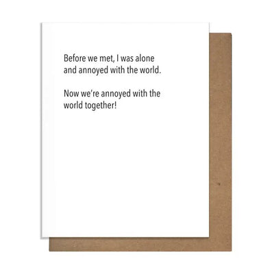 The Annoyed Together Anniversary Greeting Card from Pretty Alright Goods is letterpress printed on luxurious cotton paper, featuring black text that reads, Before we met, I was alone and annoyed with the world. Now were annoyed with the world together! Its A2 size presented with a classic brown envelope.