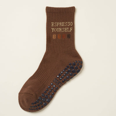 The Effortless Club Coffee Lover Grip Sock is a single brown Pilates sock with non-slip black grips, made from organic cotton. Features ESPRESSO YOURSELF and coffee beans below.