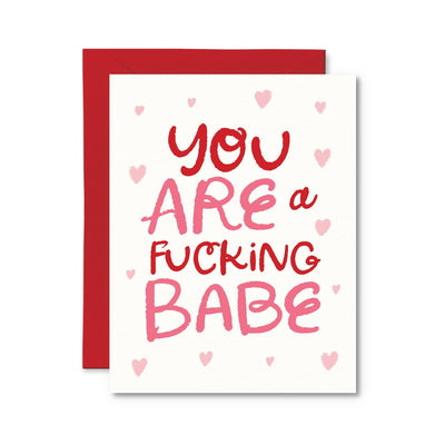 The You Are a Fucking Babe Card by Pretty by Her features bold red and pink lettering with small pink hearts, made from high-quality cardstock. It includes a responsibly sourced red envelope for a perfect expression of admiration.