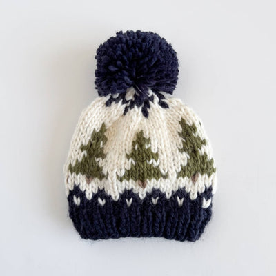 Knitted beanie with a patterned design and navy pom-pom on a white background