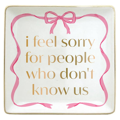 The soiree-sisters "I Feel Sorry For People Who Don't Know Us" Trinket Tray is a white square dish with a pink ribbon border and gold lettering—perfect as a gift or jewelry holder.