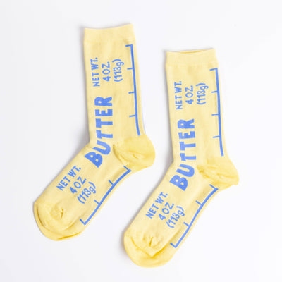 Butter - Small Crew Socks by Yellow Owl Workshop are yellow cotton crew socks styled like butter packaging, with blue text NET WT. 4 OZ (113g) and BUTTER, measurement lines, and reinforced heel and toe for comfort.