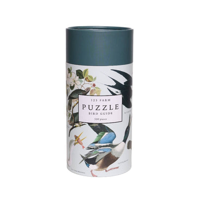 The 123 Farm Birds Puzzle – 500 Pc with Vintage Illustrations comes in a cylindrical box with a dark green lid, featuring bird and foliage artwork inspired by an organic farm.