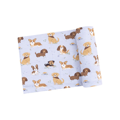 The Angel Dear Blue Best Friend Dogs Bamboo Stretch Knit Swaddle Blanket features a charming cartoon dog pattern with bones and paw prints on soft, light blue fabric. Perfect for wrapping or as a cozy cover, its versatile design makes it an ideal choice.