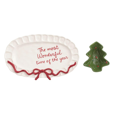 The Mud Pie Bow Tree Platter & Tidbit features an oval stoneware tray with a red ribbon and "The most Wonderful time of the year" message, paired with a festive tree-shaped tidbit dish accented by hand-painted red dots.