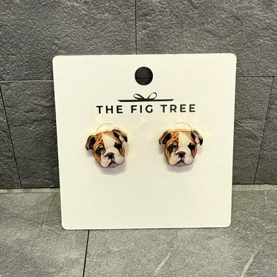 Bulldog Enamel Stud Earrings by Golden Stella, featuring bulldog face designs on gold-tone metal, displayed on a white THE FIG TREE card against a gray tiled background.