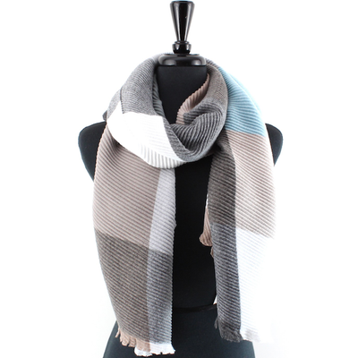 A mannequin showcases the Merrymaking Pleated Scarf by Pretty Persuasions, a large ribbed acrylic-polyester scarf with a gray, brown, white, and light blue color-block pattern draped loosely around the neck.