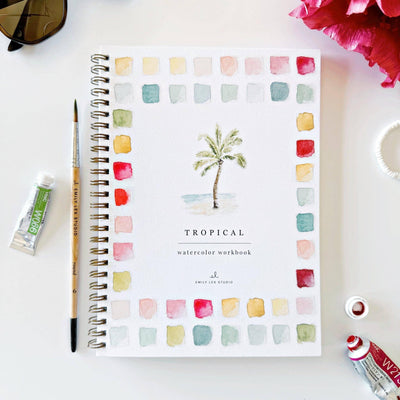 The Tropical Watercolor Workbook by emily lex studio is a spiral-bound, beginner-friendly guide featuring a palm tree and colorful swatches on the cover, surrounded by a paintbrush, paint tubes, sunglasses, and a red flower.