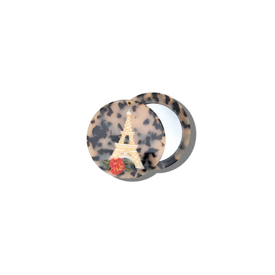 The Solar Eclipse Hand-painted Eiffel Tower Compact Mirror features a round, leopard-print design with an Eiffel Tower and red rose on the lid; shown partially open, it reveals the interior mirror.