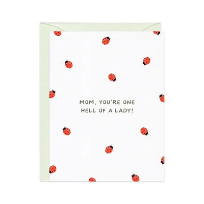 Amy Zhangs One Hell of A Lady (Bug) Mothers Day A2 greeting card features red ladybugs on white, with Mom, youre one hell of a lady! text. It has a blank interior for personalization and comes with a pale green envelope, all proudly made in the USA.