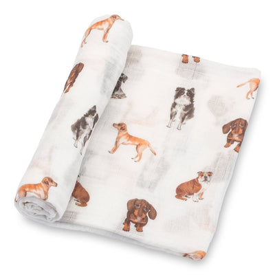 The LollyBanks Adorable Dog Print Baby Swaddle Blanket is a white cotton muslin swaddle featuring brown, black, and tan dog breeds—ideal as a cozy baby blanket or for swaddling newborns.