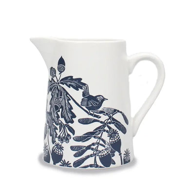 White ceramic pitcher with blue floral and bird design on a white background