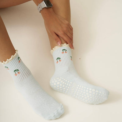 White socks with floral patterns worn by a person on a light background