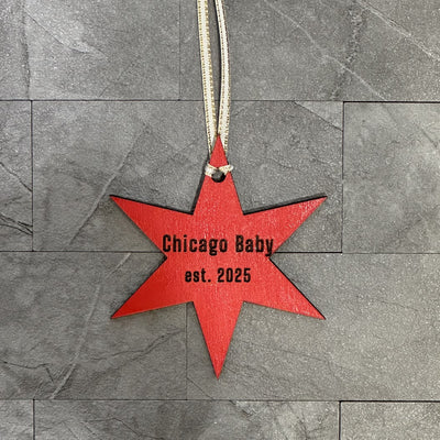 Red star-shaped ornament with 'Chicago Baby est. 2025' text on a gray stone surface