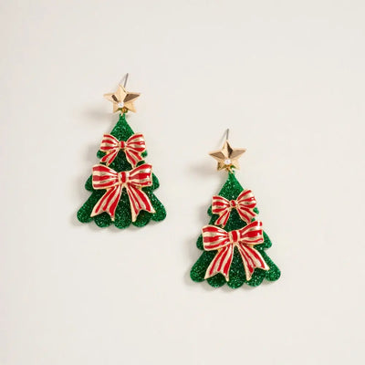 Golden Stella Christmas Tree Earrings with Red Bows, crafted from zinc and measuring 2 inches, feature gold stars and festive accents. They are displayed on a plain white background.