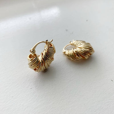 Pair of gold hoop earrings on a light gray background