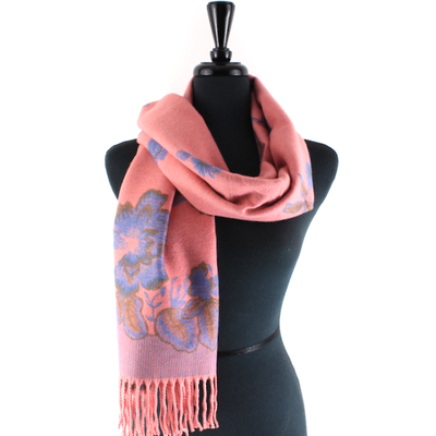 The Tahiti Garden Reversible Scarf by Pretty Persuasions, featuring pink viscose with blue and brown floral patterns and fringe, is elegantly draped on a black dress form mannequin.