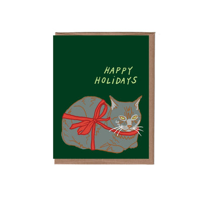 The Loaf Cat Holiday Greeting Card by La Familia Green features a gray cat with orange markings in a red ribbon on a dark green background, “HAPPY HOLIDAYS” above. Send cheer on FSC certified paper with this handmade card.