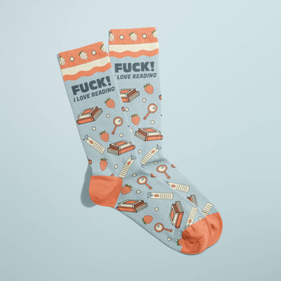The FUN CLUB Fuck! I Love Reading Socks feature light blue cotton, orange accents, books, magnifying glasses, strawberries, and the bold phrase “FUCK! I LOVE READING”—funny socks perfect for book lovers.