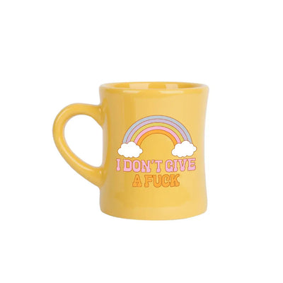 The I Dont Give A Fuck Diner Mug by Talking Out of Turn is a sassy yellow accessory featuring a rainbow and clouds illustration, boldly stating its message. Perfect for morning coffee, it adds attitude with every sip.