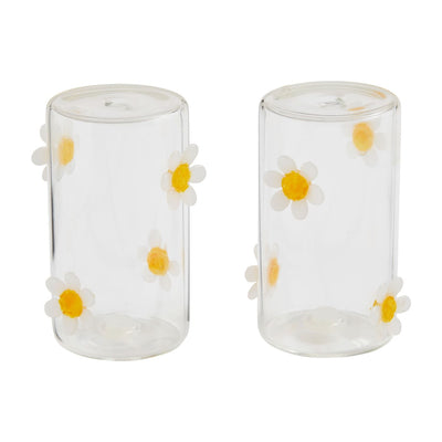 This 2-piece Daisy Salt & Pepper Set by Mud Pie features clear glass adorned with white daisies and sunny yellow centers. The cheerful floral pattern embellishes the cylindrical surfaces, creating an enchanting touch for any setting, showcasing their delightful design.