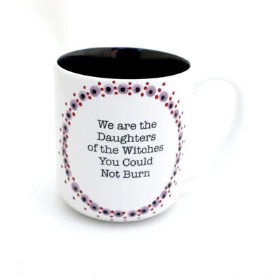 The Lenny Mud Daughters of Witches Mug features a purple and red dotted circle and the quote “We are the Daughters of the Witches You Could Not Burn.” This stylish, dishwasher-safe mug is both practical and eye-catching.